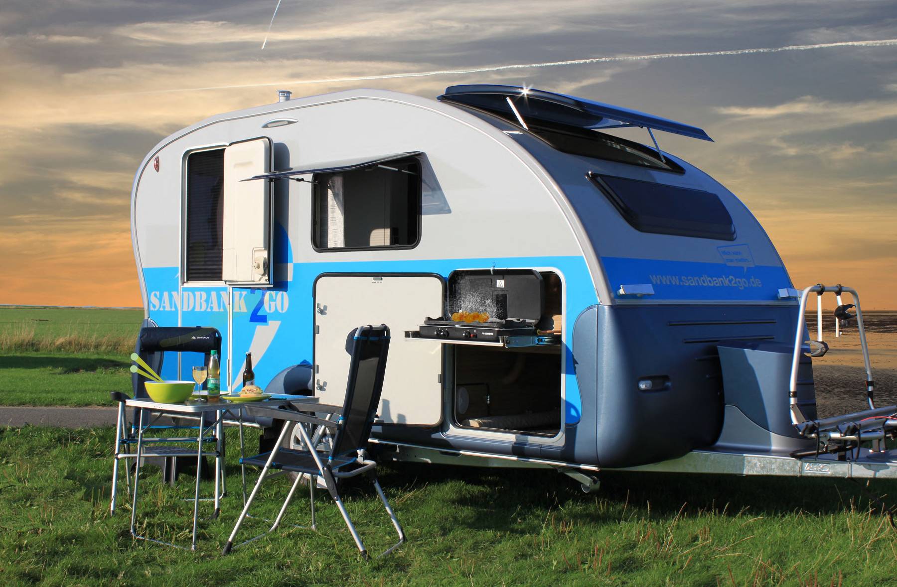 Wohnwagen mit Stuhl und Tisch davor