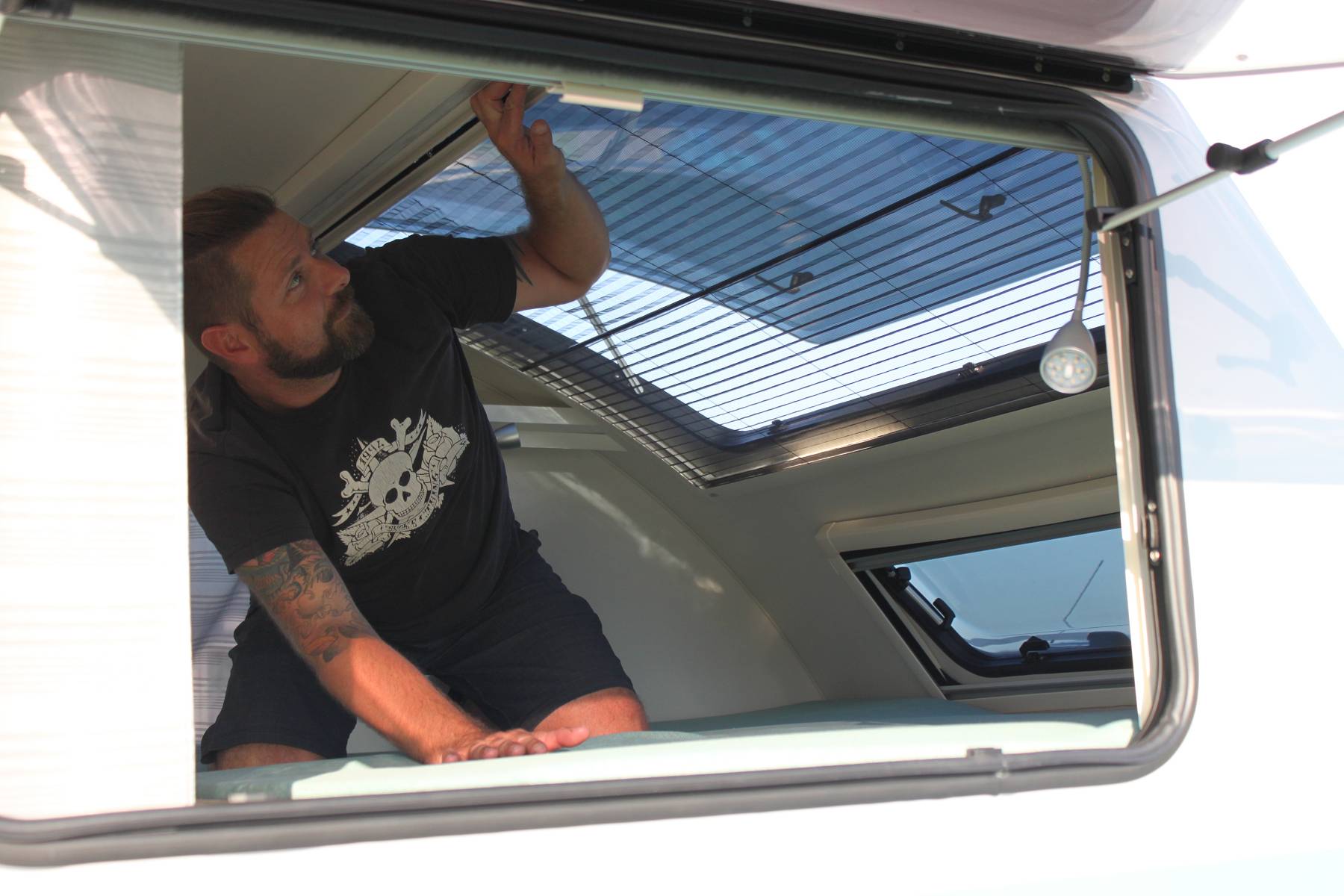 Mann öffnet Fenster Wohnwagen